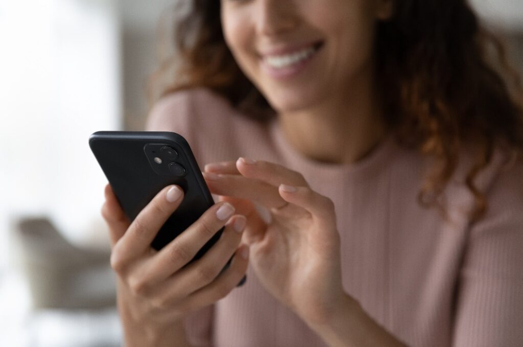 Nahaufnahme einer Frau, die mit ihrem Handy eine SMS schreibt